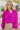 Close-up front view of model wearing the Take Me Out Top, which features a purple colored material, a collar V neck with a button, a long flowy sleeve with a smocking at the wrist, a draped bottom hem. Tucked into beige skirt.
