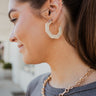 The On The Daily Earring is an ivory hoop style earring, featuring a hexagon shape with brown marbling through out.