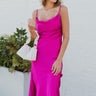 Full body front view of model wearing the Let's Dance Midi Dress, which features a fuchsia satin material, a cowl neckline, a sleeveless design with thin adjustable straps, a side slit, and a midi length.