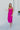 Full body front view of model wearing the Let's Dance Midi Dress, which features a fuchsia satin material, a cowl neckline, a sleeveless design with thin adjustable straps, a side slit, and a midi length.