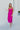 Full body front view of model wearing the Let's Dance Midi Dress, which features a fuchsia satin material, a cowl neckline, a sleeveless design with thin adjustable straps, a side slit, and a midi length.