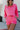 Front view of model wearing the Out Of Your League Top, which has a hot pink material, a collar neck, a long sleeve, a 3/4 button-up front, a patch-work design, and a wide cropped fit.