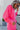 Side view of model wearing the Out Of Your League Top, which has a hot pink material, a collar neck, a long sleeve, a 3/4 button-up front, a patch-work design, and a wide cropped fit.