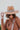 The Pretty In Paisley Hat is a wide brim hat featuring a camel colored fabric featuring a brown belt with a black and white paisley design finished with adjustable ties within for adjusted fit.