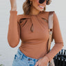 Frontal view of the Knot Yours Bodysuit that features a camel colored material, a round neckline, a long sleeve, a knot cut-out detail at the chest, a thong bottom, and a snap closure.