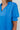 Frontal view of the Irreplaceable Top that features a royal blue material, a round neckline with a ruffle detail, a cut-out at the chest with adjustable ties, a short smocked sleeve, and a flowy fit.