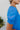 Side view of the Irreplaceable Top that features a royal blue material, a round neckline with a ruffle detail, a cut-out at the chest with adjustable ties, a short smocked sleeve, and a flowy fit.