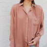 Frontal view of the Jump Start Top that features a marsala colored material, a collar neckline, a button-up front, a cuffed long sleeve, a front pocket a high-low design, and a flowy fit