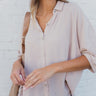 Frontal view of the Back In Session Top In Taupe that features a taupe colored material, a collar neckline, a button-up front, an oversized half sleeve, a high-low design, and a flowy fit.