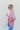 Side view of the Back In Session Top In Rose that features a rose colored material, a collar neckline, a button-up front, an oversized half sleeve, a high-low design, and a flowy fit.