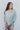 Frontal view of the Back In Session Top In Spruce that features a sage colored material, a collar neckline, a button-up front, an oversized half sleeve, a high-low design, and a flowy fit.