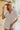 Frontal view of the At Ease Top that features an ivory colored material, a V neckline, a short cuffed sleeve, a high-low design, and a flowy fit.