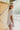 Side view of the At Ease Top that features an ivory colored material, a V neckline, a short cuffed sleeve, a high-low design, and a flowy fit.