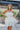 Frontal view of the Tulle Me About It Mini Dress that features a cream tulle material with a straight neckline, a sleeveless tiered design, a side zipper closure, and a mini length