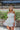 Frontal view of the Tulle Me About It Mini Dress that features a cream tulle material with a straight neckline, a sleeveless tiered design, a side zipper closure, and a mini length