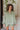 Frontal view of the On To The Next Top that features an olive green satin material, a collar neckline, a long sleeve with feather detailing at the cuff, a button-up front, and a flowy fit.