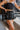 Frontal view of the One To Watch Skort that features a black faux-leather material, a thick elastic waist band with a tie detail, a tiered ruffle design, a shorts lining, and a flowy fit.
