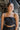 Frontal view of the Everlasting Love Crop Top that features black fabric, a straight neckline, a sleeveless design with thin adjustable straps, a back oversized bow detail, a side zipper closure, and a cropped fit.