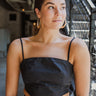 Frontal view of the Everlasting Love Crop Top that features black fabric, a straight neckline, a sleeveless design with thin adjustable straps, a back oversized bow detail, a side zipper closure, and a cropped fit.