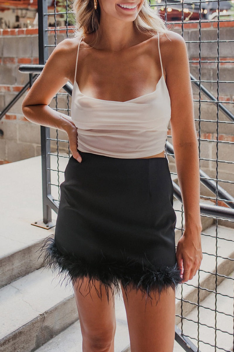 Frontal view of the I'm So Fancy Skirt that features a black colored material, a high-rise fit, a feather detailed hem, a back zipper closure, and a mini length.