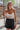 Frontal view of the Day Glow Tank Top that features an ivory sheer chiffon material, a cowl neckline, a sleeveless design with thin straps, an open tie back, and a cropped fit.