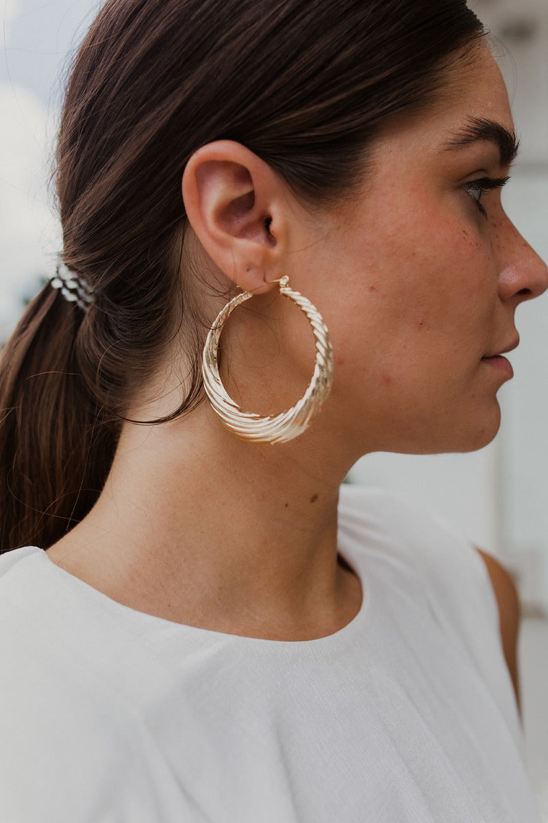 The New Classic Earring is a gold, hoop style earring featuring an edged design through out.