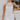 Frontal View of the Seek It Out Mini Dress that features a white colored material, a sleeveless design with a high halter neck, a mesh material at the chest, an open back, and a back zipper closure.