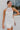 Frontal View of the Seek It Out Mini Dress that features a white colored material, a sleeveless design with a high halter neck, a mesh material at the chest, an open back, and a back zipper closure.