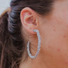 The Plus One Earring is a silver hoop featuring silver sparkles through out.