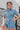 Frontal View of the Heading South Romper that features a blue colored material, a collar neckline, a short cuffed sleeve, a button-up front, two front pockets at the chest, a cinched waist, two side pockets, cuffed bottom hem, and two back pockets.