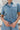 Frontal View of the Heading South Romper that features a blue colored material, a collar neckline, a short cuffed sleeve, a button-up front, two front pockets at the chest, a cinched waist, two side pockets, cuffed bottom hem, and two back pockets.