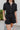 Frontal view of the Heading South Romper that features a black colored material, a collar neckline, a short cuffed sleeve, a button-up front, two front pockets at the chest, a cinched waist, two side pockets, cuffed bottom hem, and two back pockets.