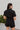 Back view of the Heading South Romper that features a black colored material, a collar neckline, a short cuffed sleeve, a button-up front, two front pockets at the chest, a cinched waist, two side pockets, cuffed bottom hem, and two back pockets.