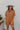 Frontal view of the Lady May Romper that features a brown fabric, a collar neckline, a short cuffed sleeve, a button-up front, two front pockets at the chest, a cuffed bottom hem, and two back pockets.