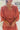 Frontal view of the Just Peachy Dress that features a ginger colored material, a rounded neckline with a tie detail and V cut-out, long sleeves, a waist tie detail, a pleated bottom, and a flowy fit.