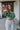 Frontal view of the In The Air Top that features a green colored metallic material, a V neckline, a half puffy sleeve, a ruched front, a smocked back, and a cropped fit.