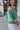 Side view of the In The Air Top that features a green colored metallic material, a V neckline, a half puffy sleeve, a ruched front, a smocked back, and a cropped fit.