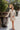 Frontal view of the Means Business Dress that features a cream colored chiffon material, a surplice lapel neckline, a long sleeve, a wrap front with a tie, and a mini length.