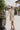Frontal view of the Means Business Dress that features a cream colored chiffon material, a surplice lapel neckline, a long sleeve, a wrap front with a tie, and a mini length.