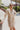 Frontal view of the Means Business Dress that features a cream colored chiffon material, a surplice lapel neckline, a long sleeve, a wrap front with a tie, and a mini length.