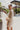 Side view of the Means Business Dress that features a cream colored chiffon material, a surplice lapel neckline, a long sleeve, a wrap front with a tie, and a mini length.