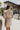 Back view of the Means Business Dress that features a cream colored chiffon material, a surplice lapel neckline, a long sleeve, a wrap front with a tie, and a mini length.