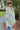 Side view of the Summer Soiree Top that features a white colored material, a multi-colored print, a collar neckline, a button-up front, a long cuffed sleeve, and a front pocket.