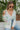 Frontal view of the Summer Soiree Top that features a white colored material, a multi-colored print, a collar neckline, a button-up front, a long cuffed sleeve, and a front pocket.