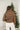 Back view of model wearing the Next Adventure Puffer Jacket in Brown that has a brown nylon material, a puffer design, a long sleeve, a zip-up front, and front pockets. This jacket comes with a packable pouch to take!