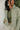 Front view of model wearing the New Adventure Puffer Jacket in Moss that has a moss green nylon material, a puffer design, a long sleeve, a zip-up front, and front pockets. 