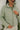 Close front view of model wearing the New Adventure Puffer Jacket in Moss that has a moss green nylon material, a puffer design, a long sleeve, a zip-up front, and front pockets. 