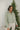 Front view of model wearing the New Adventure Puffer Jacket in Moss that has a moss green nylon material, a puffer design, a long sleeve, a zip-up front, and front pockets. 