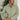Front view of model wearing the New Adventure Puffer Jacket in Moss that has a moss green nylon material, a puffer design, a long sleeve, a zip-up front, and front pockets. Model holding a packable pouch!