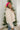 Side view of model wearing the New Adventure Puffer Jacket in Cream that has a cream nylon material, a puffer design, a long sleeve, a zip-up front, and front pockets. 
